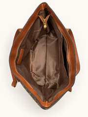 Open interior of the dark brown Coach-branded replica monogram everyday tote bag with brown lining and gold zipper hardware