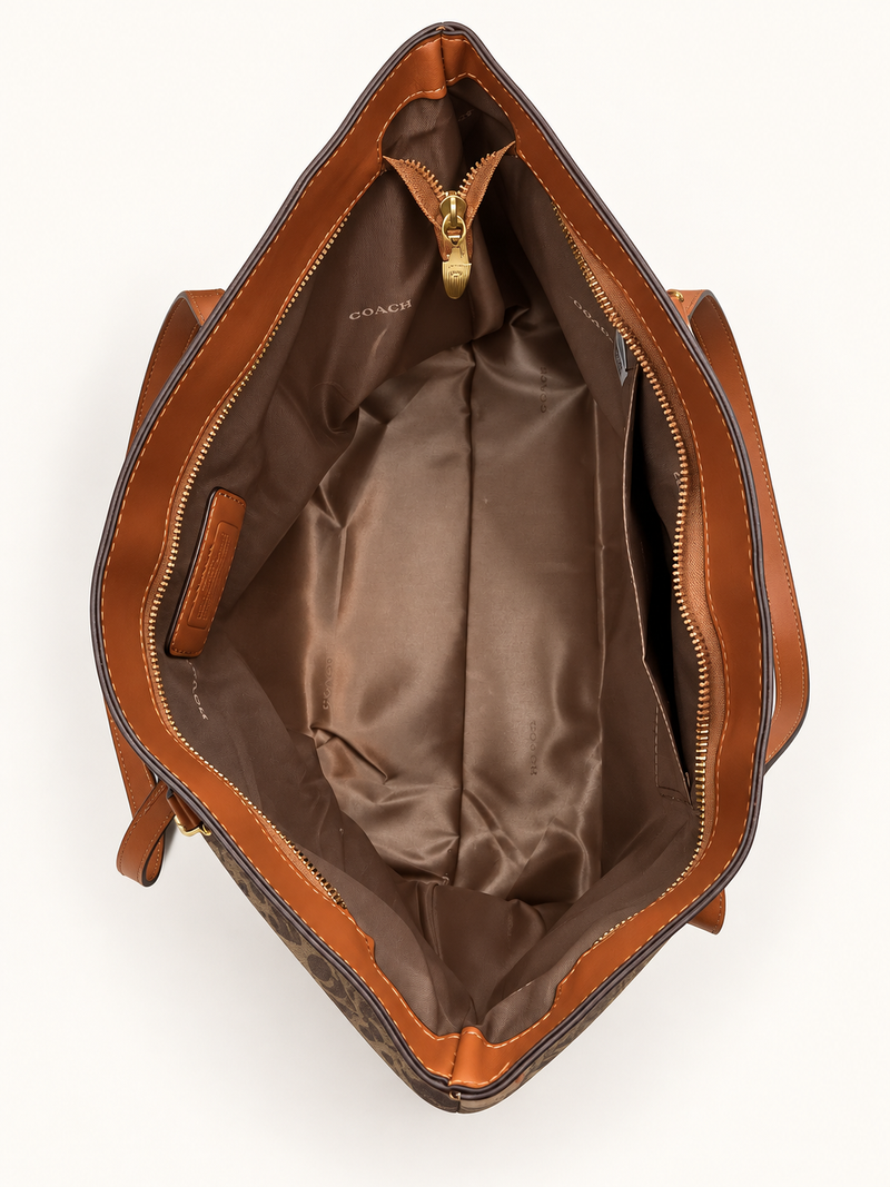 Open interior of the dark brown Coach-branded replica monogram everyday tote bag with brown lining and gold zipper hardware